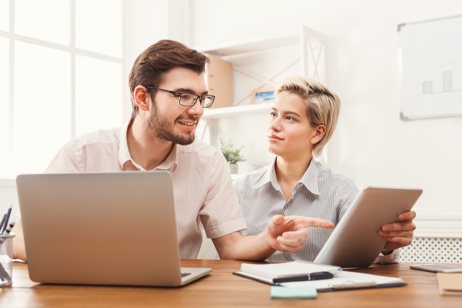 Couple of young business partners working at modern office - Coworker Mag